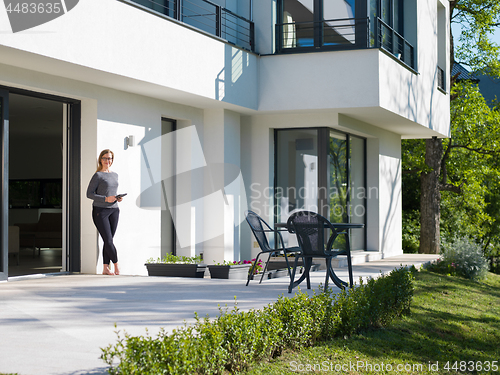 Image of women using tablet computer in front of luxury home villa