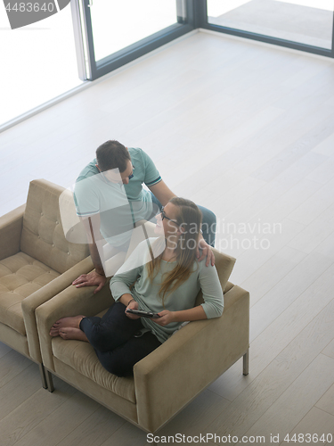 Image of couple relaxing at  home with tablet computers