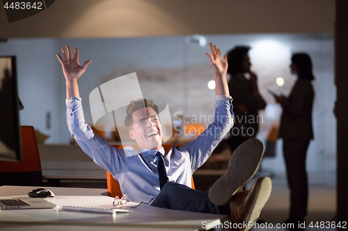 Image of businessman sitting with legs on desk at office