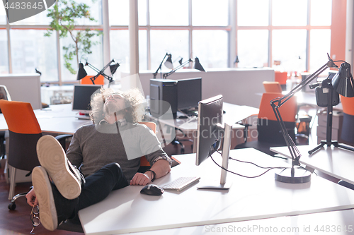 Image of businessman sitting with legs on desk