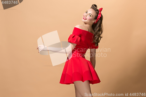 Image of Beautiful young woman with pinup make-up and hairstyle. Studio shot on pastel background