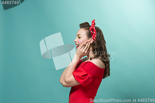 Image of Beautiful young woman with pinup make-up and hairstyle. Studio shot on pastel background