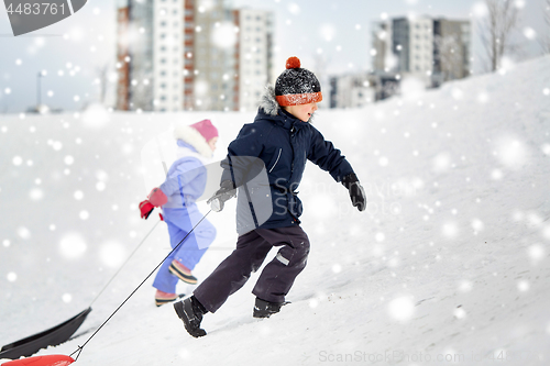 Image of kids with sleds climbing snow hill in winter