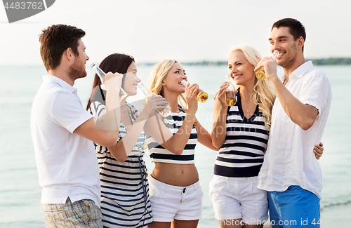 Image of happy friends drinking non alcoholic beer on beach