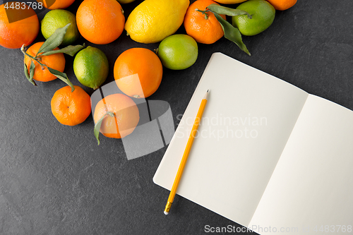 Image of close up of fruits and notebook on slate table top