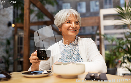 Image of senior woman drinking coffee at street cafe