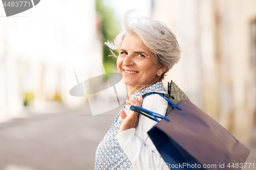 Image of senior woman with shopping bags in city