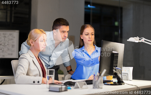 Image of business team with computer working late at office