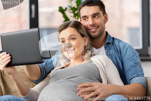 Image of man and pregnant woman with tablet pc at home