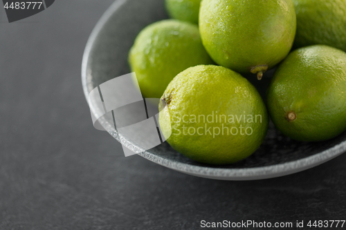 Image of close up of whole limes in bowl on slate table top