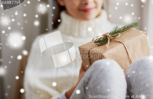 Image of girl with christmas gift sitting on sill at home
