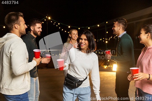 Image of friends with drinks dancing at rooftop party