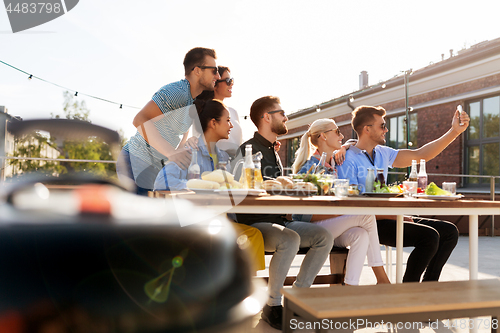 Image of happy friends taking selfie at rooftop party