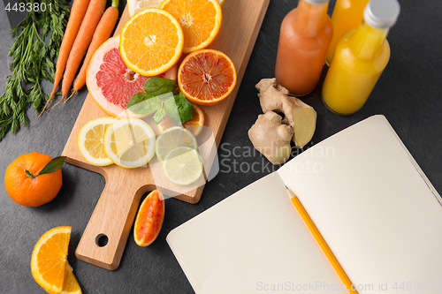 Image of close up of fruits, juices and notebook on table