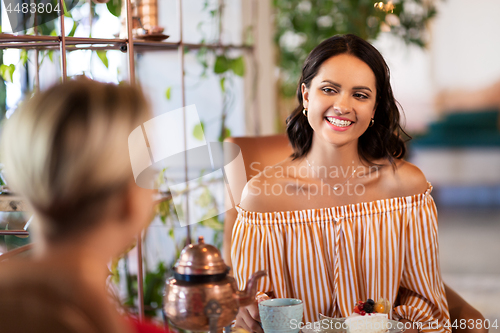 Image of female friends drinking coffee and talking at cafe