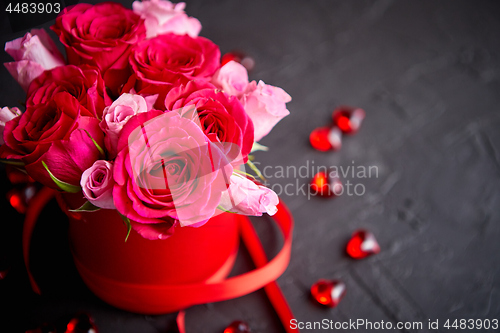 Image of Pink roses bouquet packed in red box and placed on black stone background