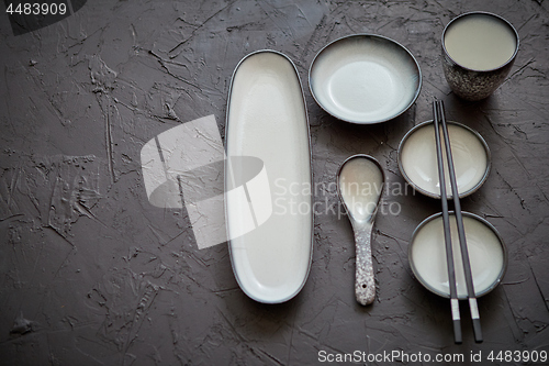 Image of Set of empty ceramic dishes for sushi and rolls on a black stone table