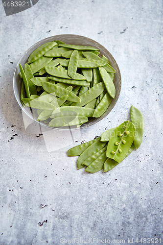 Image of Fresh green peas in white ceramic bowl on gray stone background