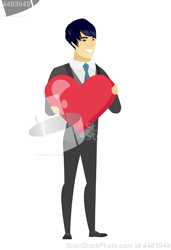 Image of Asian groom holding a big red heart.