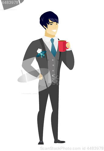 Image of Young asian groom holding cup of coffee.