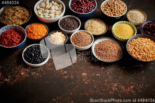 Image of Various superfoods in smal bowls on dark rusty background