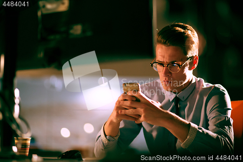 Image of man using mobile phone in dark office