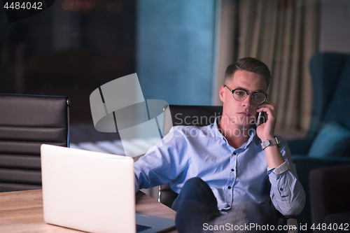 Image of businessman using mobile phone in dark office