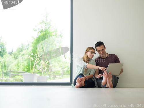 Image of couple using laptop on the floor at home