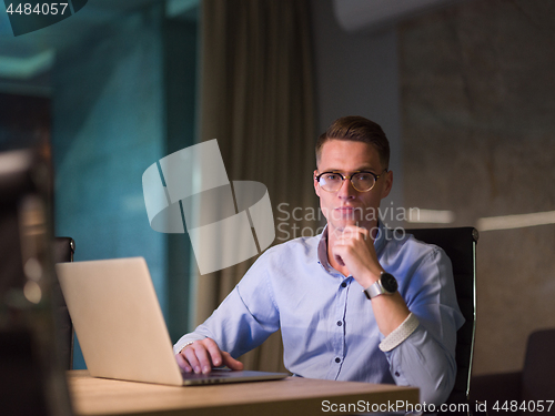 Image of man working on laptop in dark office