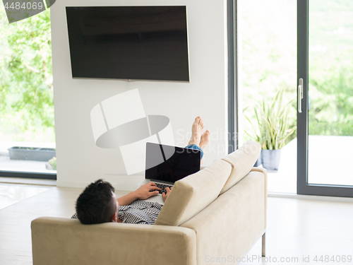 Image of Man using laptop in living room