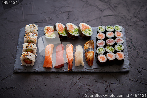 Image of Sushi rolls set with salmon and tuna fish served on black stone board