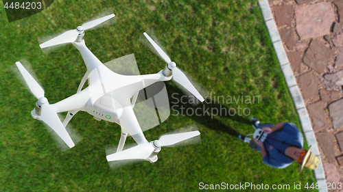 Image of Drone Quadcopter (UAV) In Air Above Pilot With Remote Controller