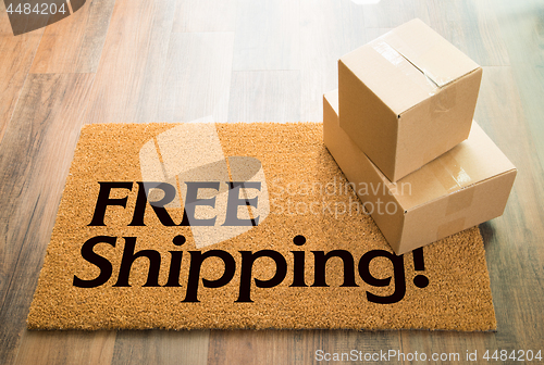 Image of Free Shipping Welcome Mat On Wood Floor With Shipment of Boxes