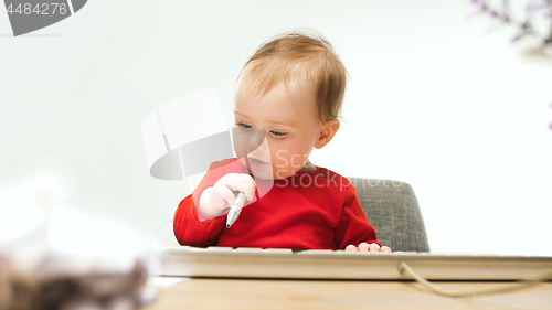 Image of Happy child baby girl toddler sitting with keyboard of computer isolated on a white background