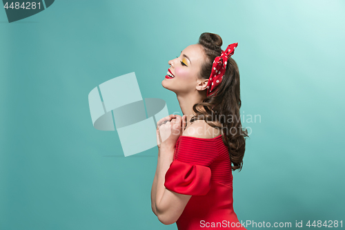 Image of Beautiful young woman with pinup make-up and hairstyle. Studio shot on pastel background
