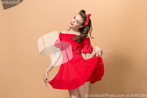 Image of Beautiful young woman with pinup make-up and hairstyle. Studio shot on pastel background