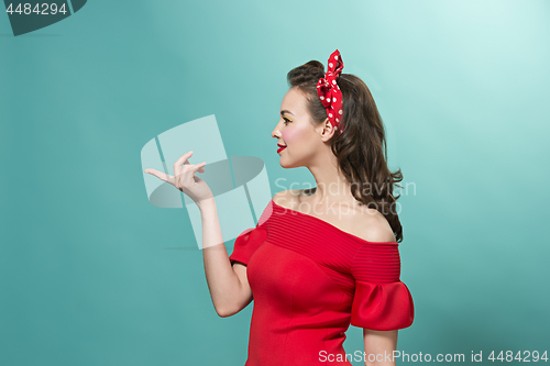 Image of Beautiful young woman with pinup make-up and hairstyle. Studio shot on pastel background