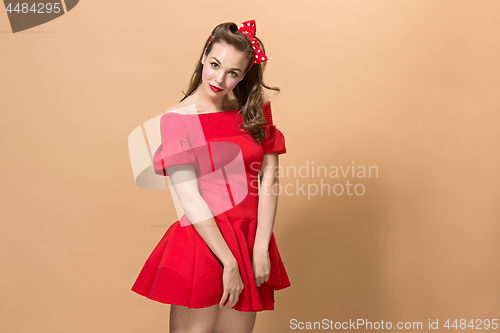 Image of Beautiful young woman with pinup make-up and hairstyle. Studio shot on pastel background