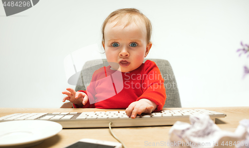 Image of Happy child baby girl toddler sitting with keyboard of computer isolated on a white background