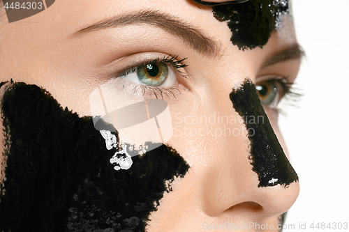 Image of Young beautiful woman applying a mask for the face of the therapeutic black mud. Spa treatment