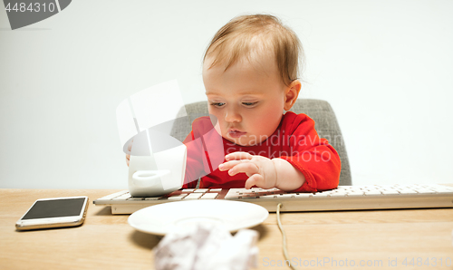 Image of Happy child baby girl toddler sitting with keyboard of computer isolated on a white background