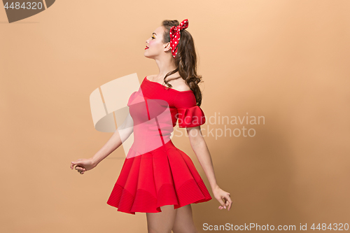 Image of Beautiful young woman with pinup make-up and hairstyle. Studio shot on pastel background