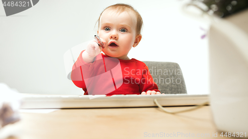 Image of Happy child baby girl toddler sitting with keyboard of computer isolated on a white background