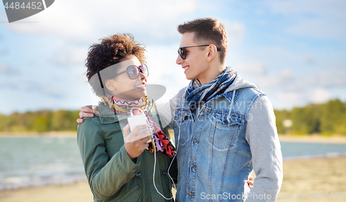 Image of couple with smartphone and earphones over beach