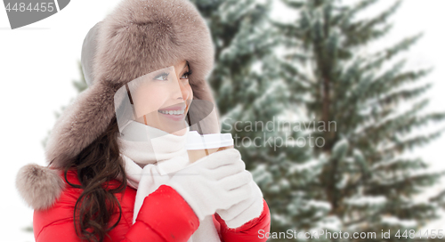 Image of woman in fur winter hat with coffee over fir trees