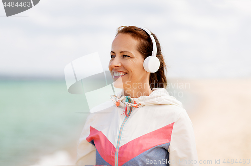 Image of smiling woman with headphones on beach