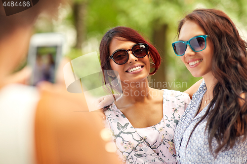 Image of woman photographing her friends in summer park