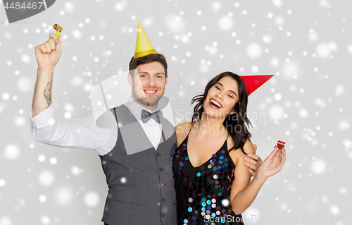 Image of happy couple with party blowers having fun