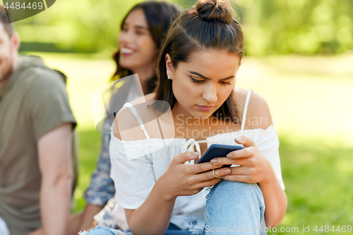 Image of woman using smartphone with friends at summer park