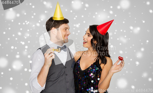 Image of happy couple with party blowers having fun